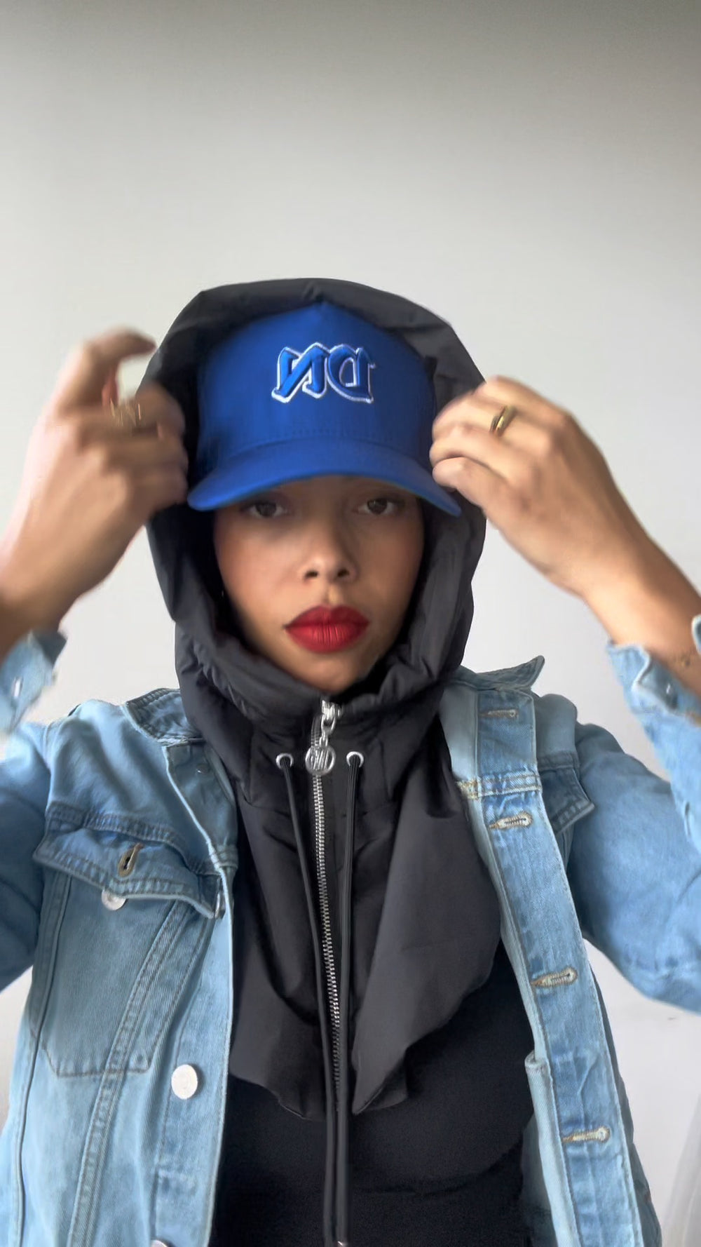 Capuche DNAST portée relevée avec une veste en jean et une casquette bleue